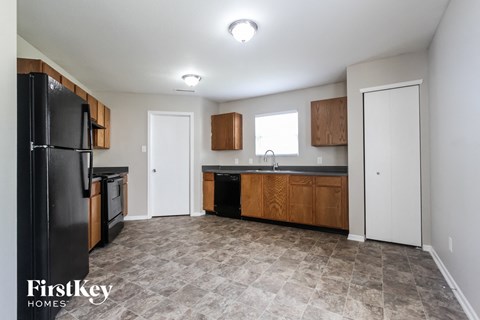 A kitchen with a black fridge and wooden cabinets.