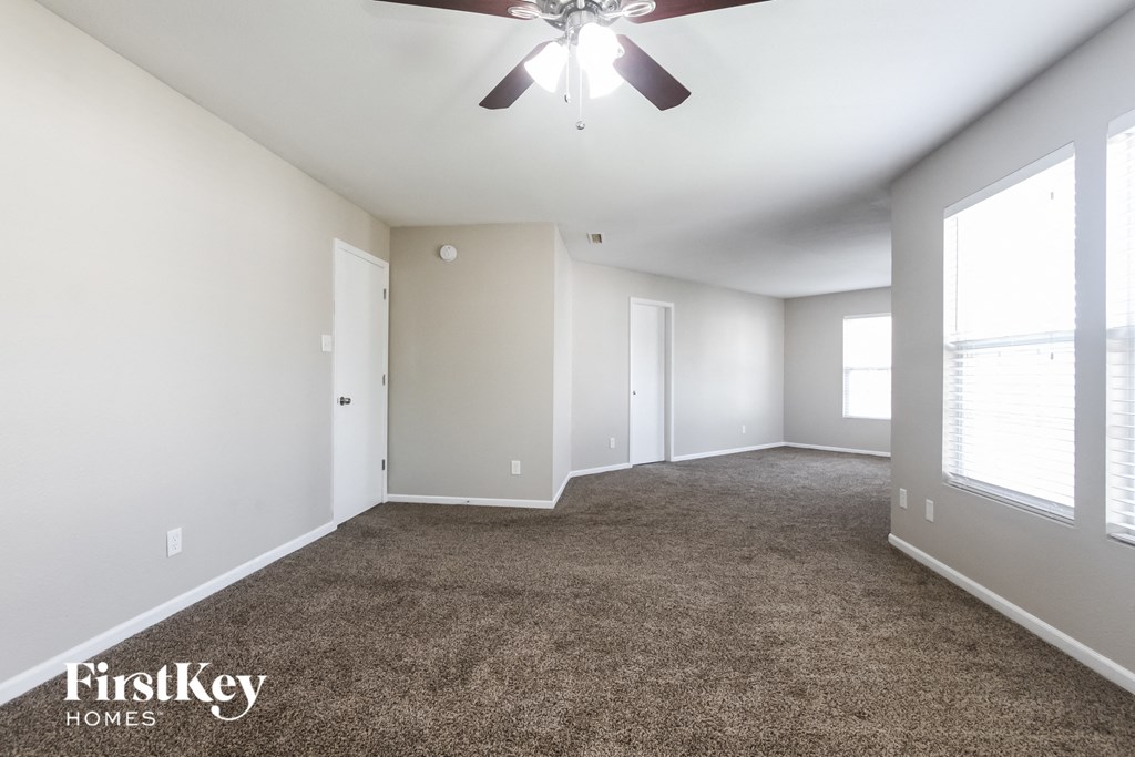 A spacious room with a ceiling fan and carpeted floor.