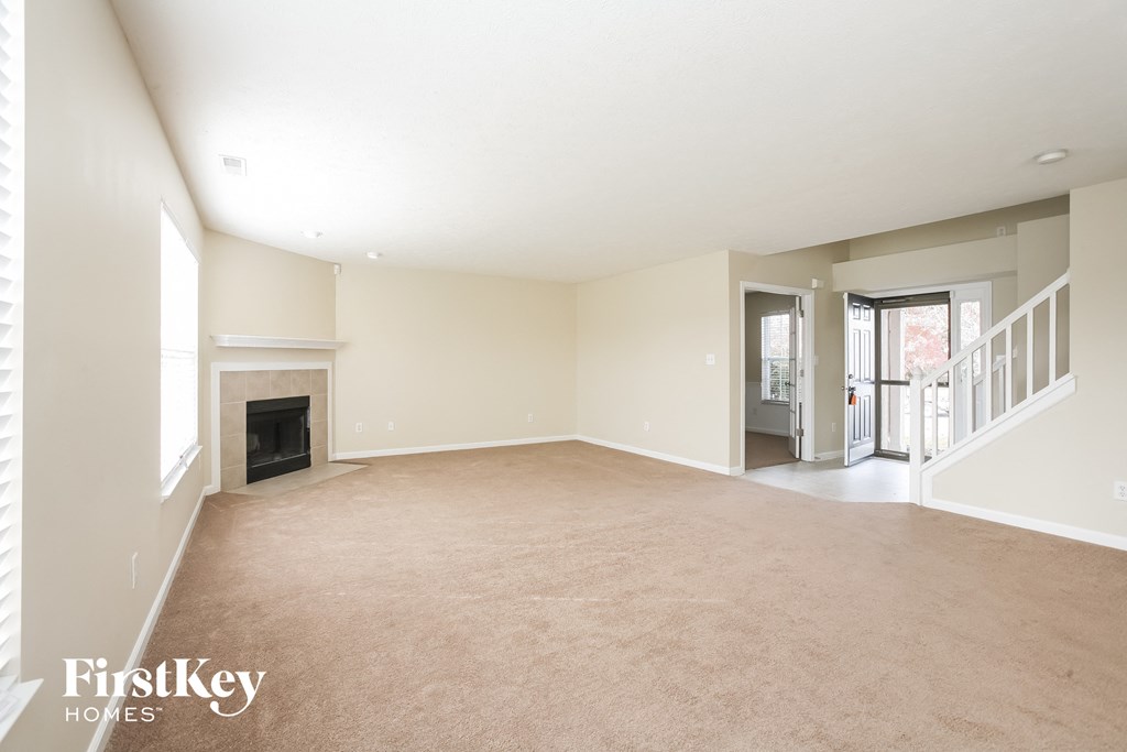 an empty living room with a fireplace and a staircase