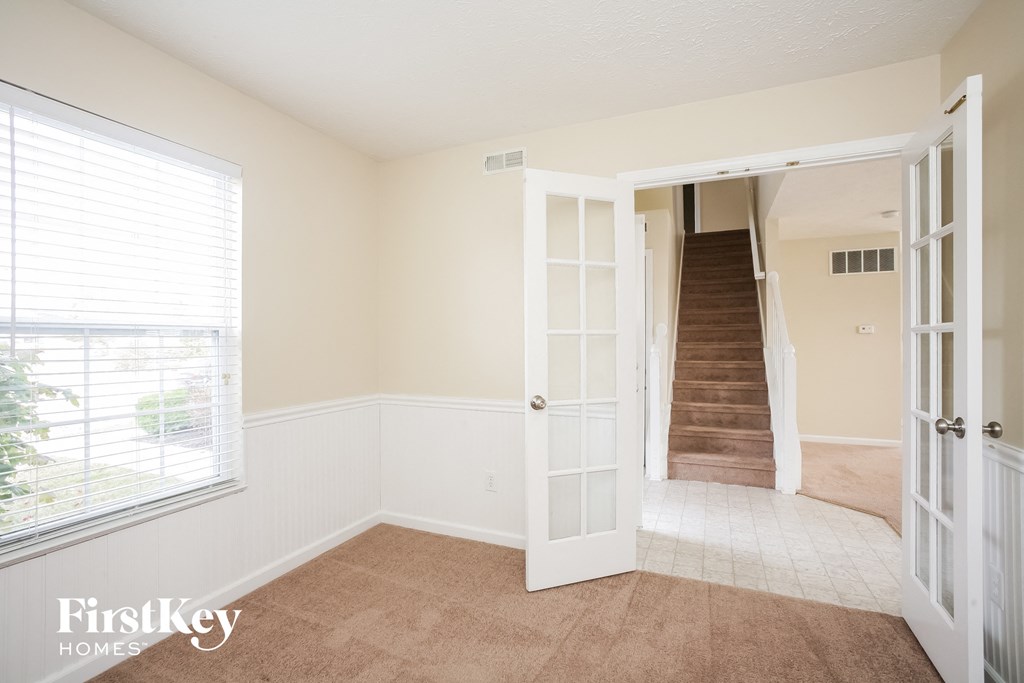a living room with a door to a staircase and a window