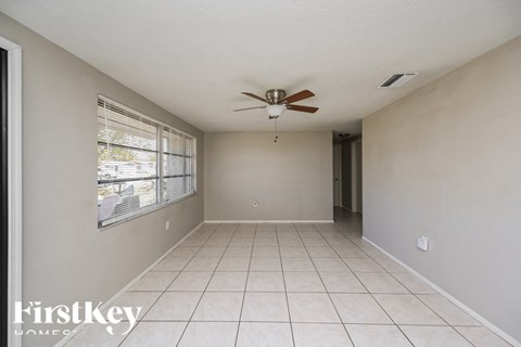 A spacious room with a ceiling fan and tiled floor.