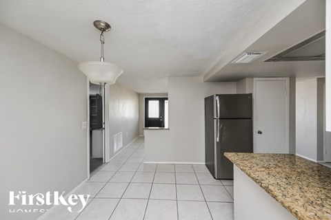 A kitchen with a granite counter top and a black fridge.