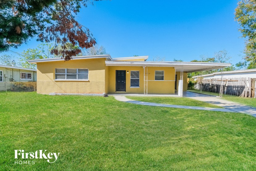 A yellow house with a white roof and a green lawn in front.