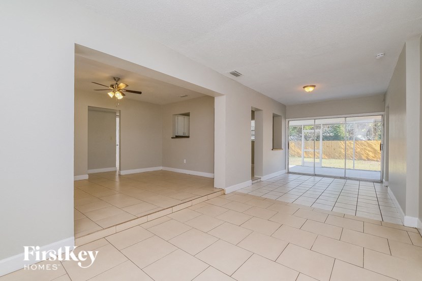 A spacious room with a ceiling fan and sliding glass doors leading to a balcony.