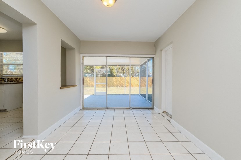 A spacious room with a tiled floor and a view of the outdoors through a sliding glass door.
