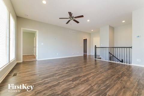 A spacious room with wooden flooring and a ceiling fan.