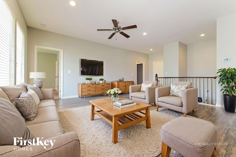A living room with a beige couch, a wooden coffee table, and a flat-screen TV mounted on the wall.
