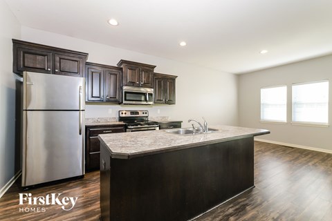 A kitchen with dark wood cabinets and a stainless steel refrigerator.