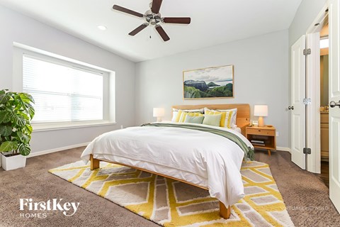 A bedroom with a bed, a ceiling fan, and a rug.