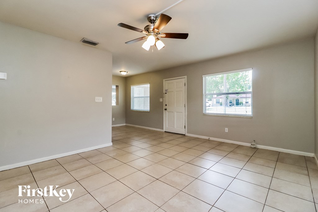 A spacious room with a ceiling fan and tiled flooring.