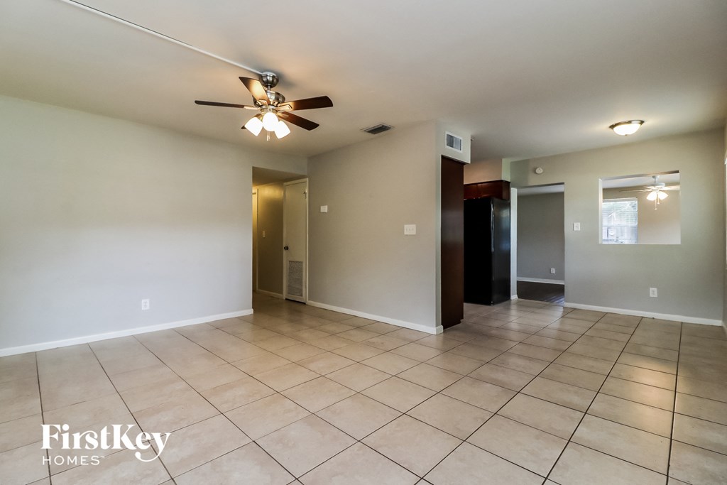A spacious room with a ceiling fan and tiled flooring.