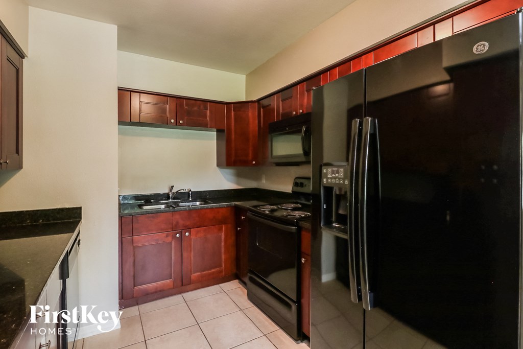 A kitchen with a black refrigerator and wooden cabinets.