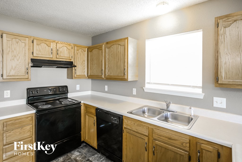 a kitchen with wood cabinets and black appliances and a sink