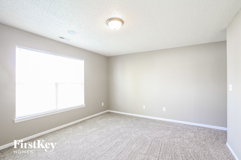an empty room with a large window and carpet