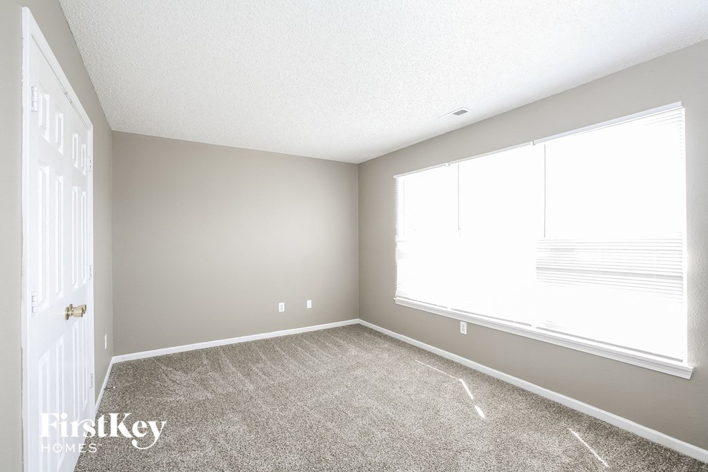 an empty room with a large window and carpet