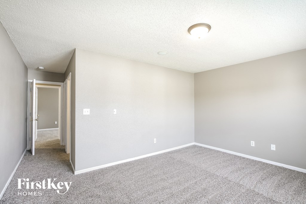 an empty living room with carpet and a door to a hallway