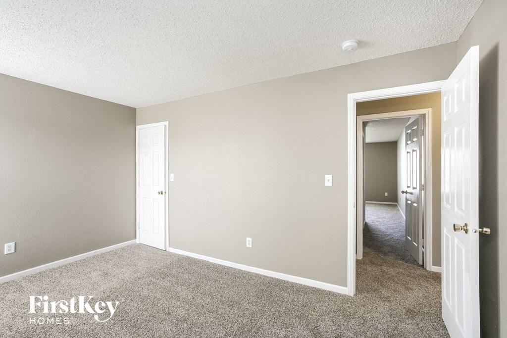 a bedroom with a carpeted floor and a hallway to a closet
