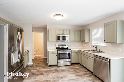 A kitchen with a refrigerator, sink, and stove.