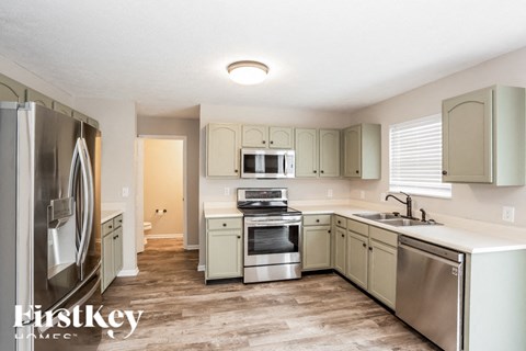 A kitchen with a refrigerator, sink, and stove.