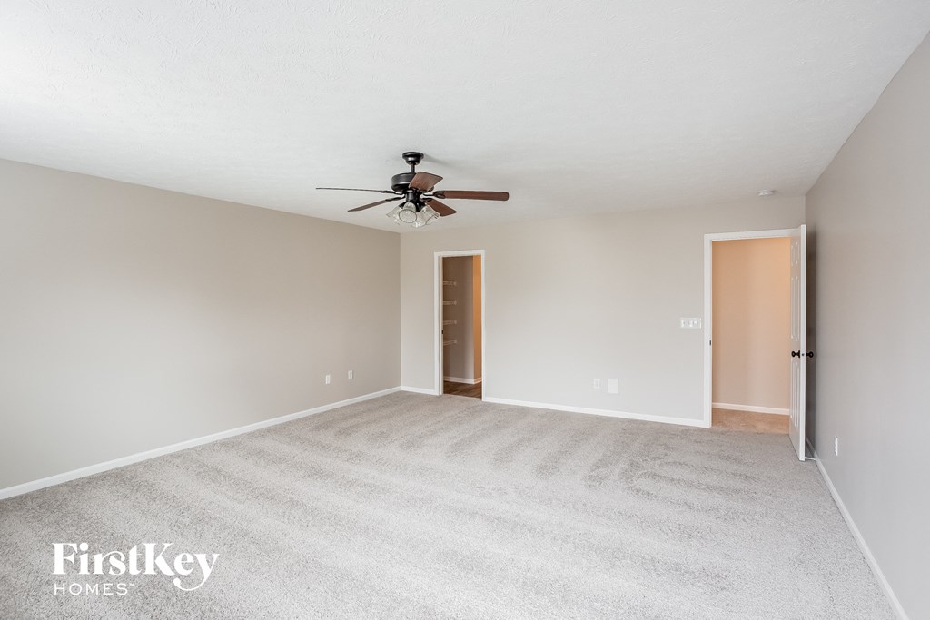 A room with a carpeted floor and a ceiling fan.