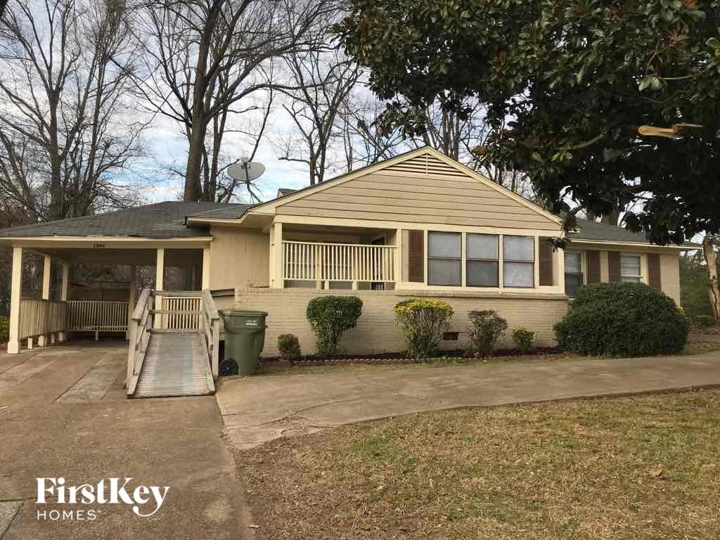 A house with a porch and a green trash can in front.