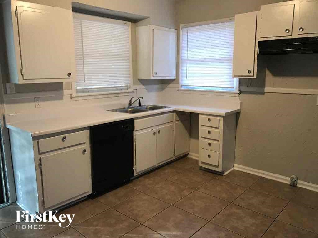 A kitchen with white cabinets and a black dishwasher.