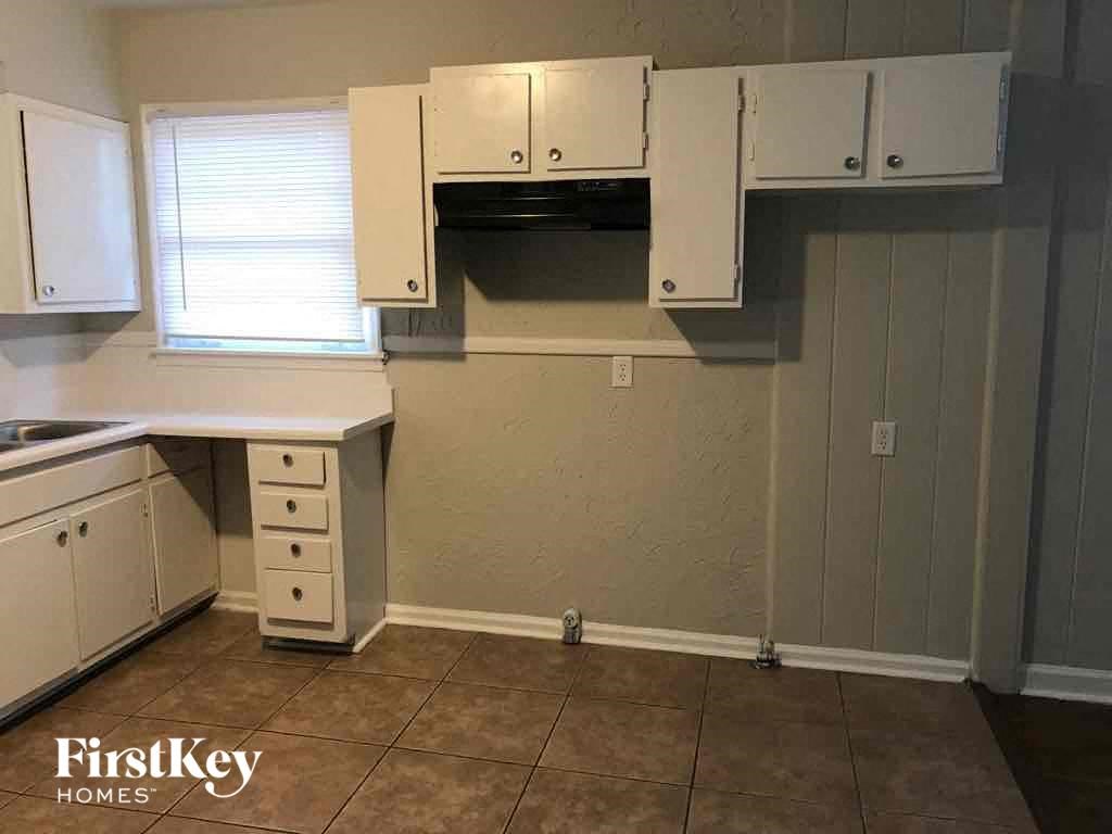 A kitchen area with a desk and cabinets.