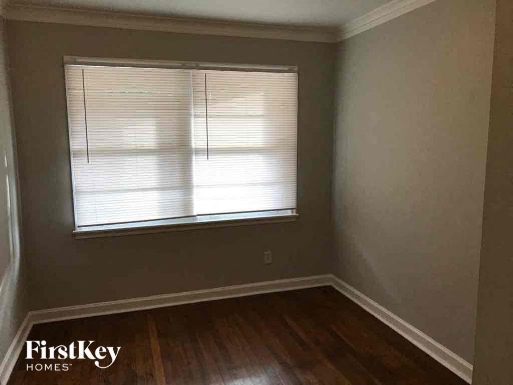 A room with wooden floors and a window with blinds.
