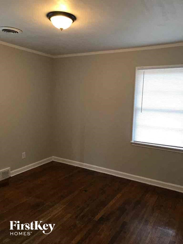 A room with wooden floors and a window with blinds.