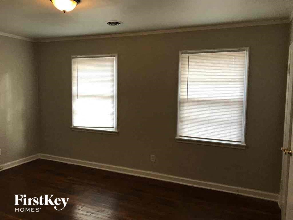 A room with two windows and wooden floors.