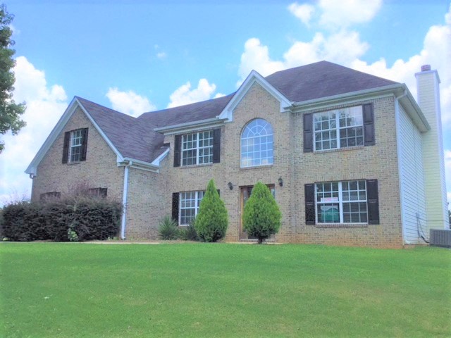 A large house with a grey roof and a green lawn in front.
