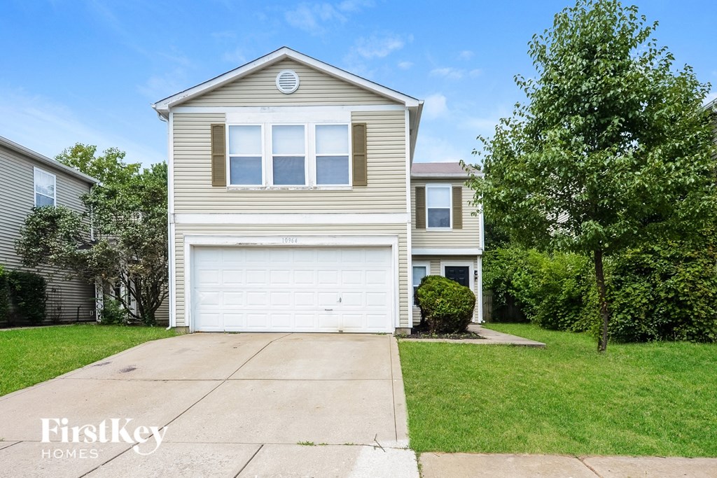 A beige house with a white garage door is for sale.