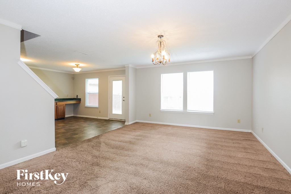 A spacious room with a carpeted floor and a chandelier hanging from the ceiling.
