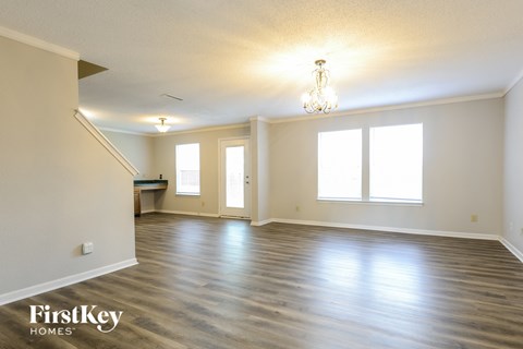 A spacious room with wooden floors and a chandelier.