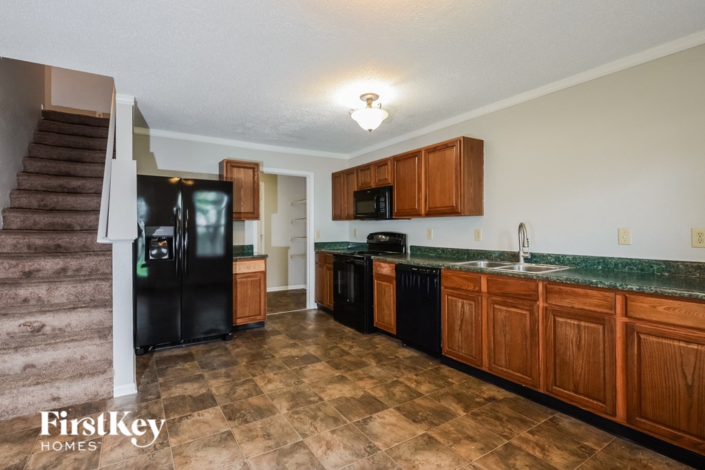 A kitchen with brown cabinets and a black fridge.