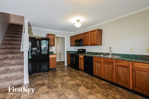 A kitchen with brown cabinets and a black fridge.