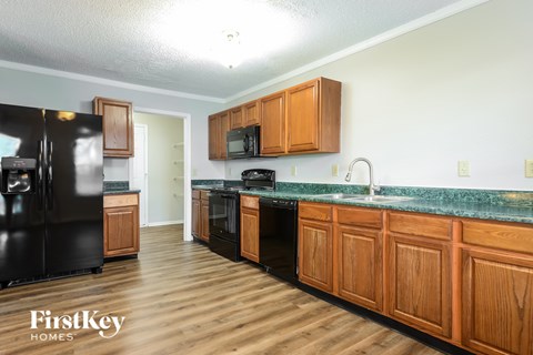 A kitchen with wooden cabinets and a black refrigerator.