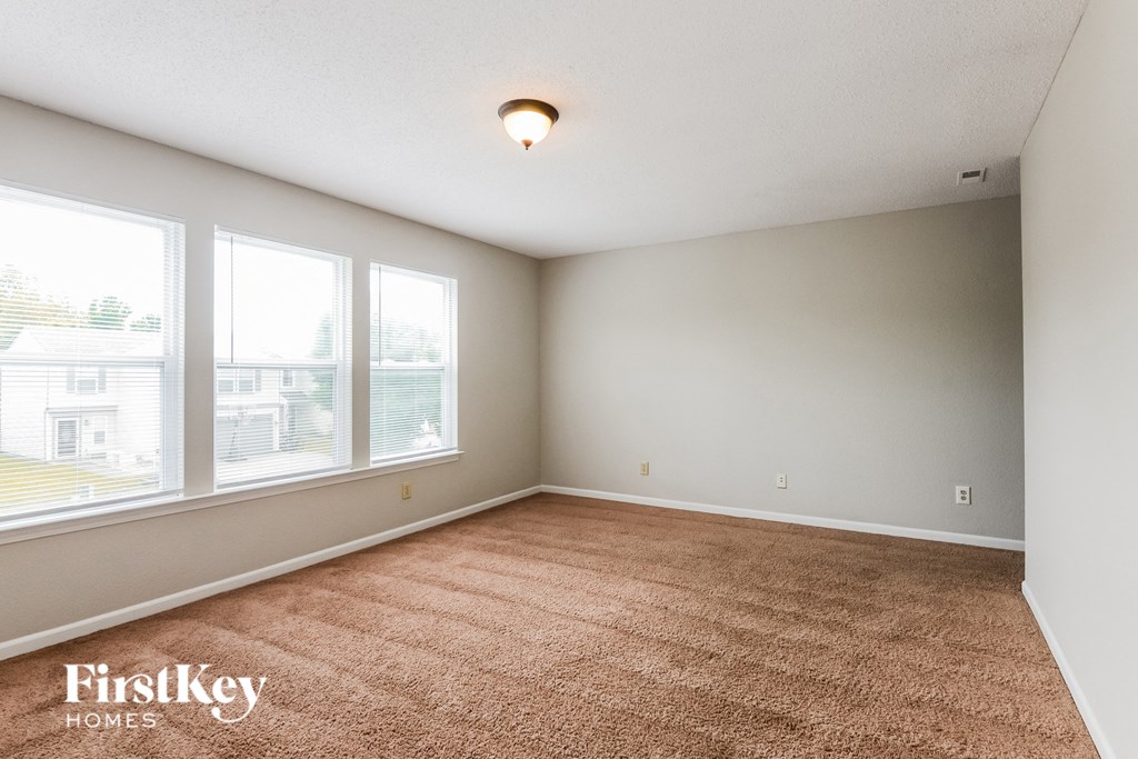 A room with a carpeted floor and a window overlooking a building.