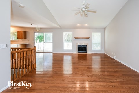 A spacious living room with wooden floors and a ceiling fan.
