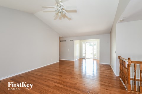 A spacious room with wooden floors and a ceiling fan.