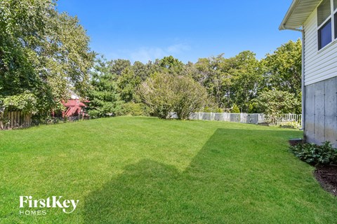 A lush green lawn with trees and a house in the background.
