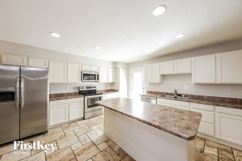 A kitchen with a refrigerator, oven, microwave, and sink.