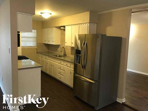 A kitchen with a stainless steel refrigerator and white cabinets.
