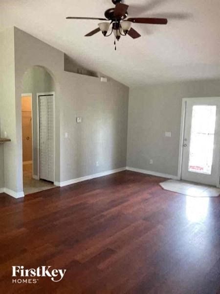 an empty living room with wood floors and a ceiling fan