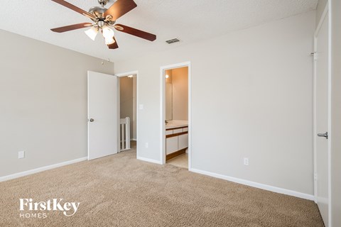 a spacious living room with a ceiling fan and a carpet