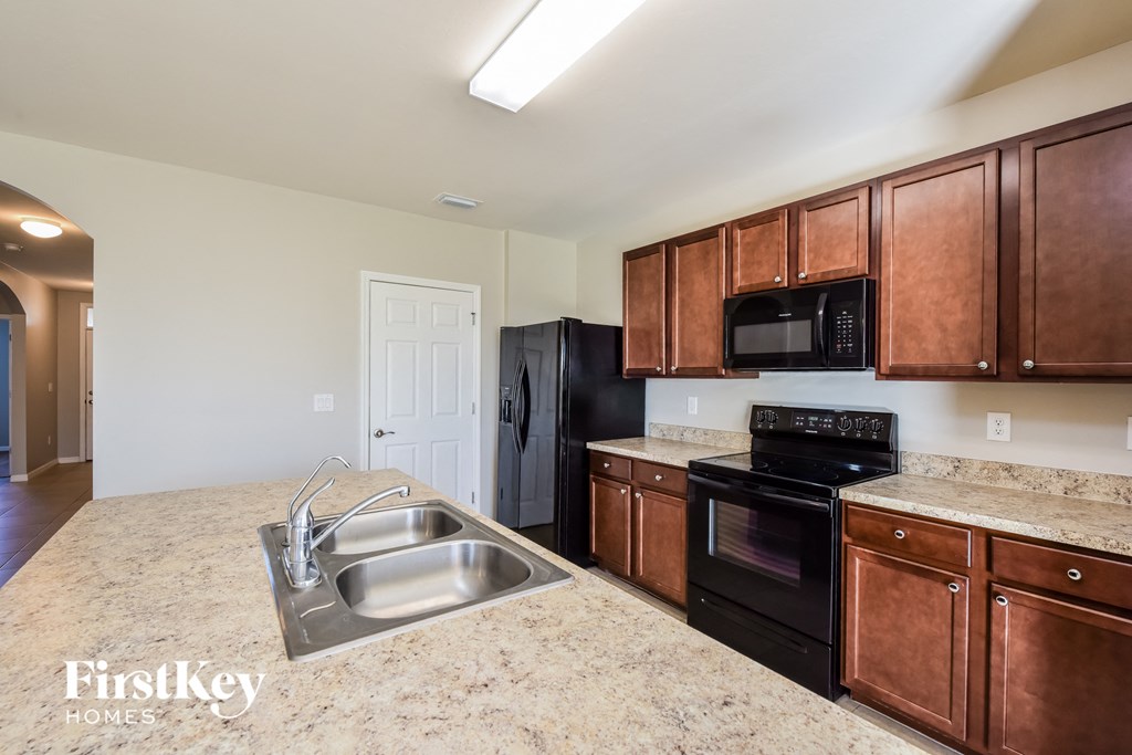 a kitchen with black appliances and brown cabinets and granite counter tops
