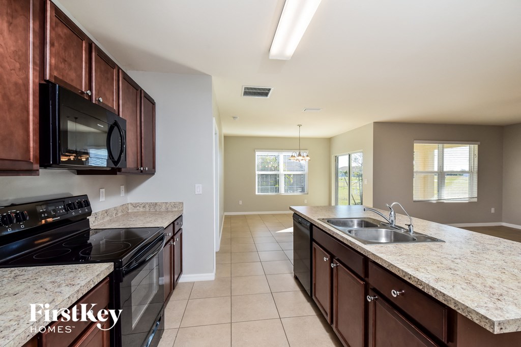 full kitchen with granite counter tops and black appliances and dark wood cabinets