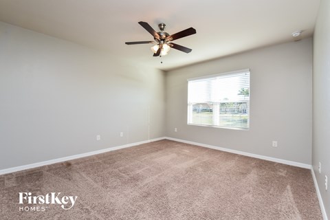 the spacious living room with ceiling fan and carpet