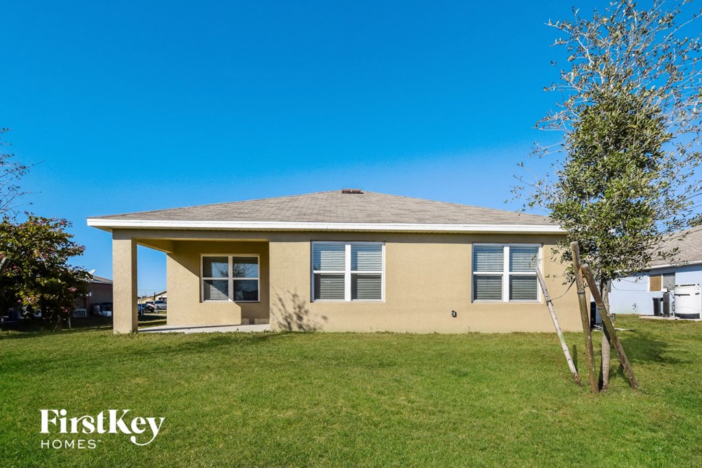 a yellow house with a lawn and a tree