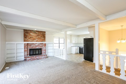 A large open living room with a fireplace and a brick wall.